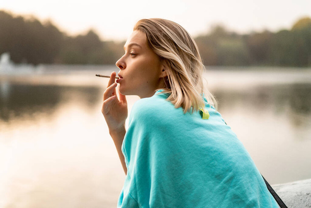 Young beautiful woman smokes a cigarette. Urban atmosphere, autu - Valokuva, kuva