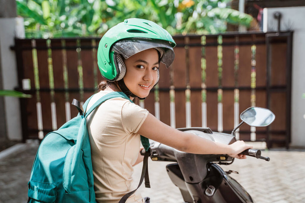 Beautiful young girl asian carrying bag to school riding motorcycle - Fotó, kép