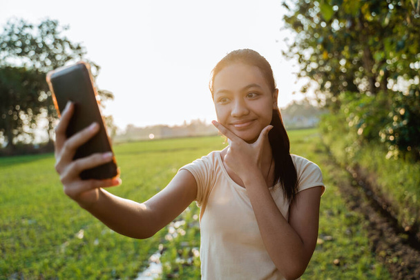 portrait of a beautiful young girl looking while holding a cellphone take a selfie - Valokuva, kuva