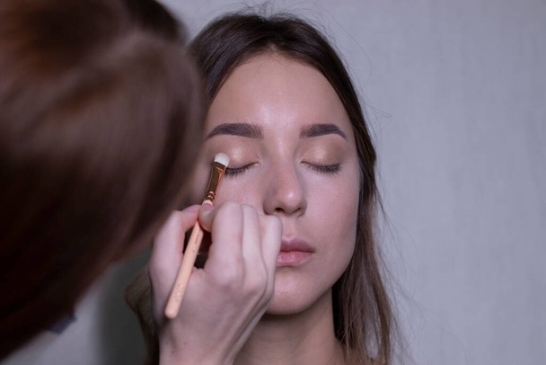 le processus d'application du maquillage à une belle brune. concept beauté, modélisation et cosmétique - Photo, image