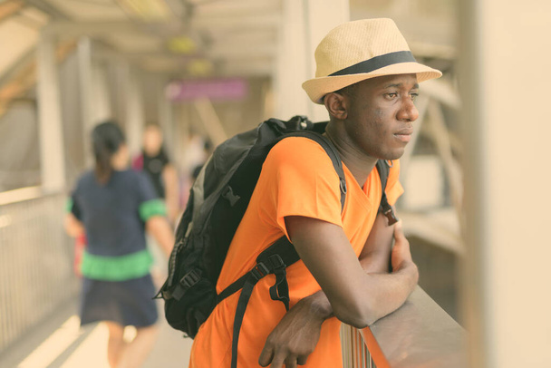 Fiatal fekete afrikai turista gondolkodás közben nézett el a gyaloghíd metró Bangkokban Thaiföld - Fotó, kép