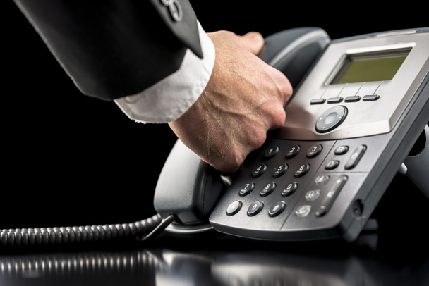 Empresário fazendo uma chamada em um telefone fixo
 - Foto, Imagem