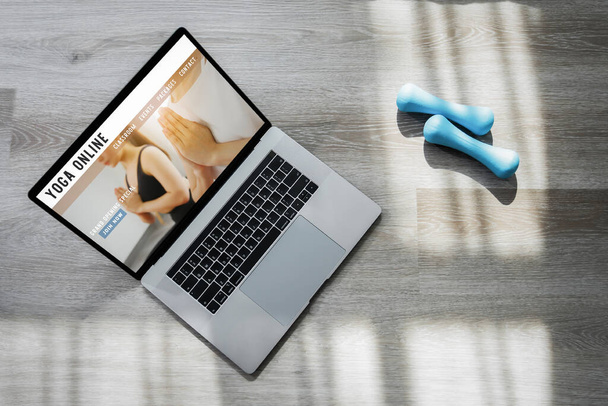 Online jóga honlap internetes tanterem laptop és kék súlyzók szürke fa háttér. - Fotó, kép