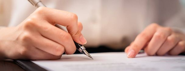 Επιχειρηματίας που υπογράφει οικονομικό συμβόλαιο και κρατά το χέρι στυλό βάζοντας υπογραφή μετά την επίτευξη συμφωνίας. - Φωτογραφία, εικόνα