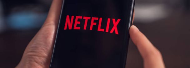 Bangkok, Thailand - October 19, 2020 : Hand use Netflix app on apple iPhone X screen. Netflix is an international leading subscription service for watching TV episodes and movies. - Photo, Image