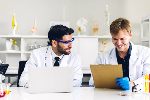 Profesjonalne dwa naukowiec człowiek badania i praca robi chemiczny eksperyment podczas gdy robi analyzing i mieszanie ciecz w probówce. - Zdjęcie, obraz