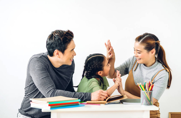 Portret cieszyć szczęśliwy uśmiechnięty miłość azjatyckiej rodziny ojciec i matka z małą azjatycką dziewczyną uczenia się i pisania w książce z ołówkiem podejmowania prac domowych w domu.Koncepcja edukacji - Zdjęcie, obraz