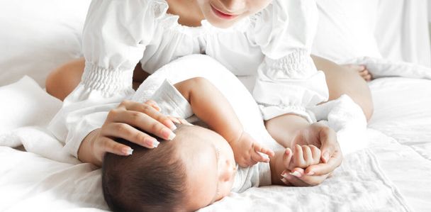 Muotokuva nauttia onnellinen rakkaus perhe aasialainen äiti leikkii suloinen pieni aasialainen baby.Mom koskettaa söpö poika hetkiä hyvää aikaa valkoinen makuuhuone. - Valokuva, kuva