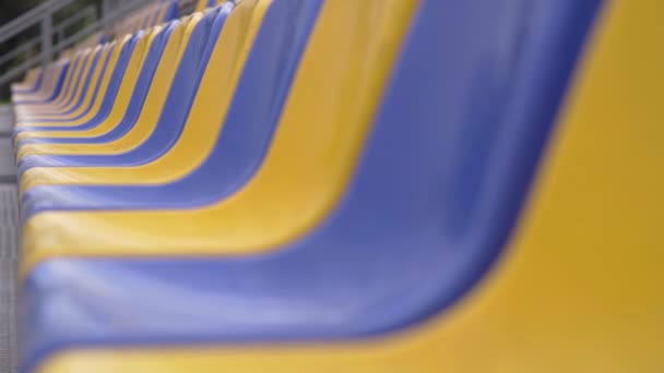 4k, Prázdné řady plastových sedadel na stadionu. Žlutá a modrá místa na tribuně sportovní arény bez diváků a fanoušků - Záběry, video