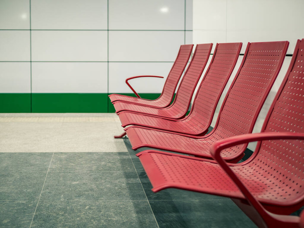 Sillas rojas metálicas alineadas para esperar en una estación de metro o metro. - Foto, Imagen