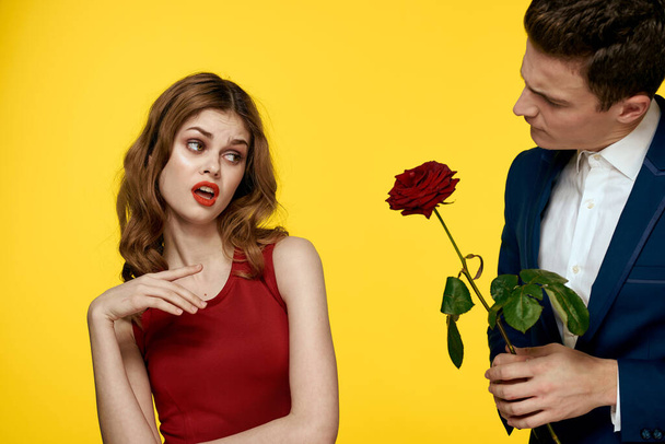 Fiatal bájos pár rózsa kapcsolat romantika ajándék, mint egy életmód sárga elszigetelt háttér - Fotó, kép
