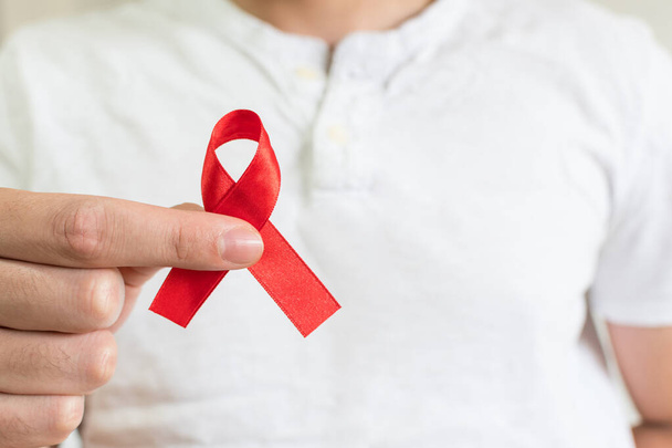 A young female with a white shirt holding an AIDs red ribbon - Foto, afbeelding