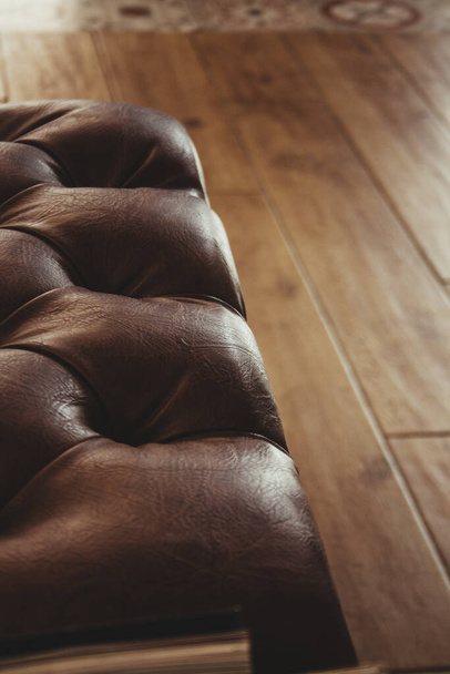 An embossed brown leather sofa on the wooden floor - Foto, imagen