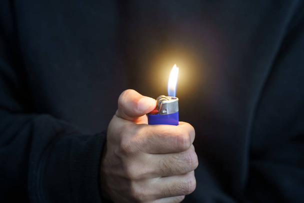 A closeup shot of a man holding a lighter with the burning flame - Fotó, kép