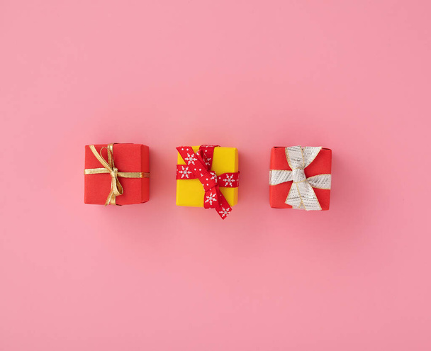 A closeup of multi-colored gift boxes in the pink background, Christmas mood - Φωτογραφία, εικόνα