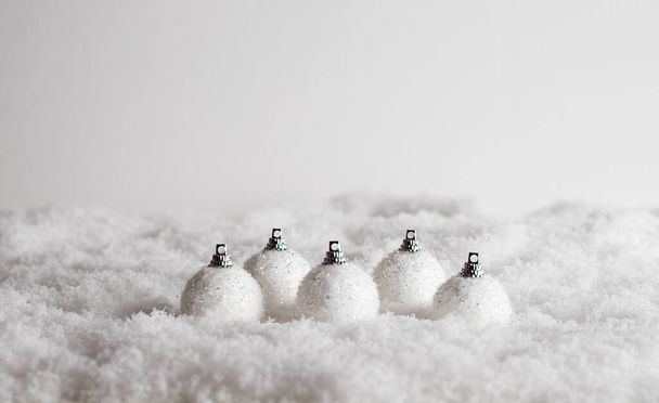 A closeup of five decorative Christmas balls in the snow, Christmas mood in the white background - Foto, afbeelding