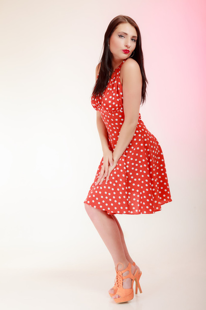 Full length pinup girl woman in retro red dress blowing a kiss - Photo, Image