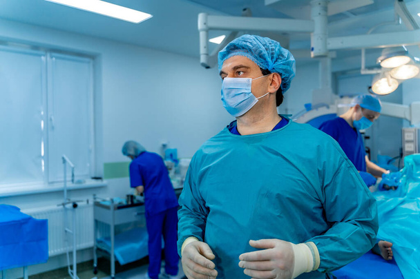 Portrait of a doctor or medical specialist. Horizontal portrait. Man in scrubs. Operating room background with blue light. Closeup. - Foto, immagini