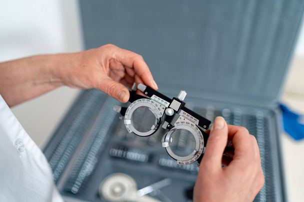 Medical device for examining eyesight of patient. Woman holding ophthalmology glasses. - Foto, Imagen