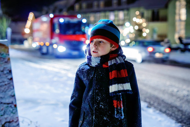 Grappig jongetje in kleurrijke kleren die buiten spelen tijdens de sneeuwval. Actieve vrije tijd met kinderen in de winter op koude besneeuwde dagen. Gelukkig gezond kind op kerstmarkt in Duitsland - Foto, afbeelding