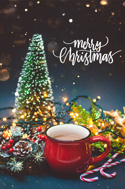 Ένας καφές σε κόκκινο κύπελλο με χριστουγεννιάτικα φώτα και διακόσμηση με Καλά Χριστούγεννα απόσπασμα - Φωτογραφία, εικόνα