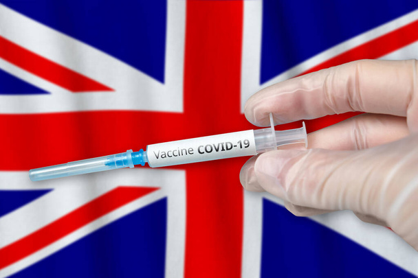Concepto de vacunación contra el Coronavirus COVID-19 en el Reino Unido de Gran Bretaña e Irlanda del Norte con mano y jeringa de médico - Foto, Imagen