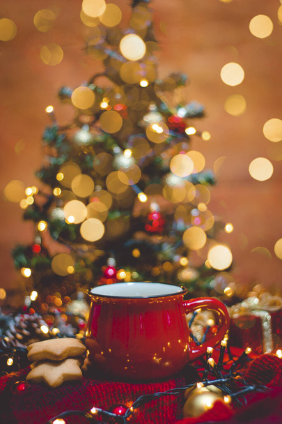 Красная кружка горячего кофе с рождественскими огнями, свежим печеньем и елкой - Фото, изображение
