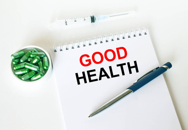 Text Good Health written in a notebook with a blue pen and a bunch of pills. Can be used as a medical concept - Foto, imagen