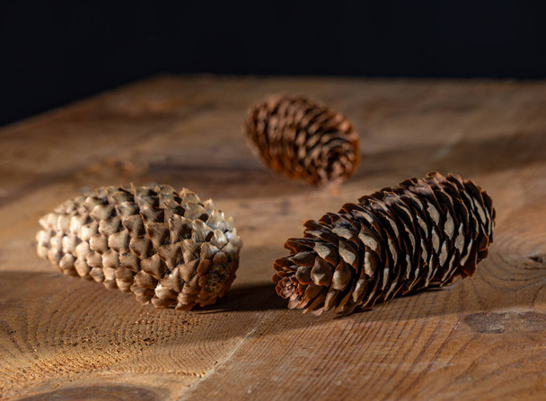 Три ялинкові конуси на дерев'яному столі
 - Фото, зображення