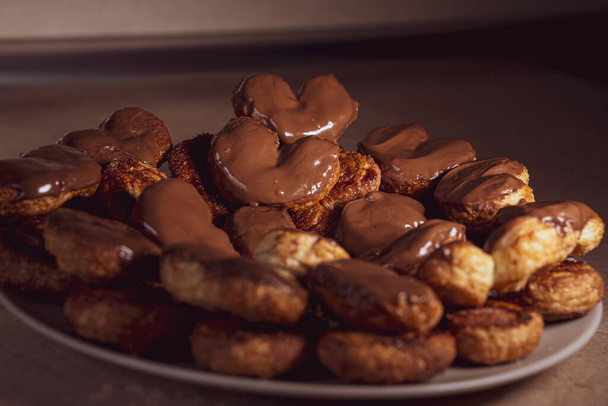 Tabakta çikolata kaplı palmier bisküviler. Kalp şeklinde poğaça, domuz kulağı, avuç içi kurabiye, fil kulağı, Fransız kalbi, ayakkabı tabanı.. - Fotoğraf, Görsel