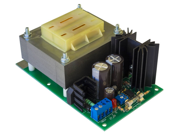 Close-up van AC DC voeding met transformator en elektronische componenten met radiatoren en rode LED op de groene print. Geïsoleerd op witte achtergrond. Hoge kwaliteit macro fotografie. - Foto, afbeelding