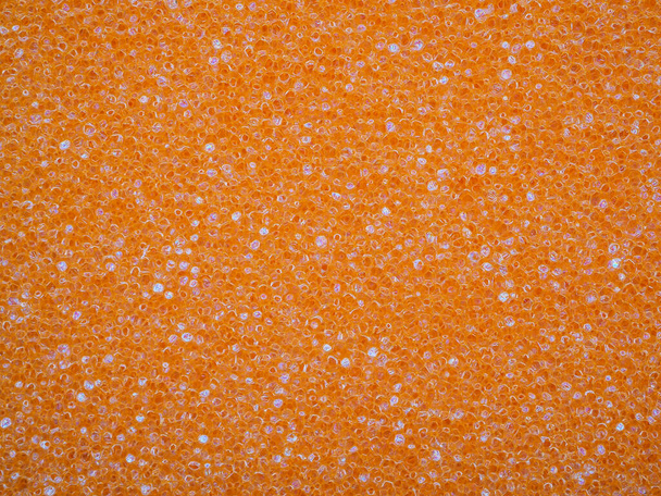 Close-up van poreuze textuur van oranje spons. Kristallijn korrelig ontwerp voor achtergrond of behang. Hoge kwaliteit macro fotografie. - Foto, afbeelding
