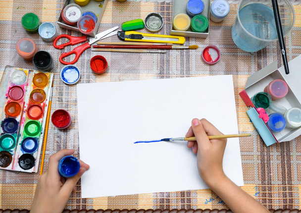 Beyaz bir kağıda suluboya çizen bir kız evde sanatsal bir eser yaratıyor. - Fotoğraf, Görsel