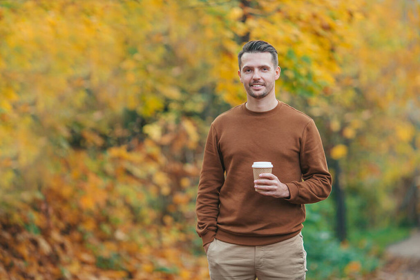 Young man drinking coffee in autumn park outdoors - Foto, imagen