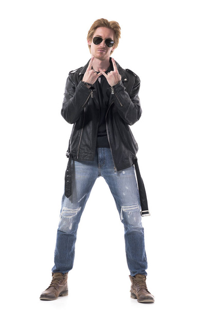 Stylish macho attitude young redhead man in leather jacket showing heavy metal horns hand sign. Full body isolated on white background. - 写真・画像