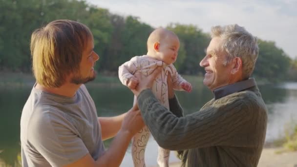 Abuelo sosteniendo al bebé en brazos afuera. Vinculación de los abuelos con los nietos. - Imágenes, Vídeo