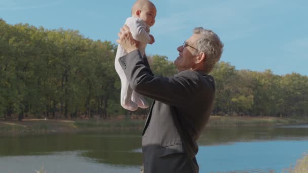Grootvader die baby 's buiten in de armen houdt. Grootouder binding met kleinkind. - Video