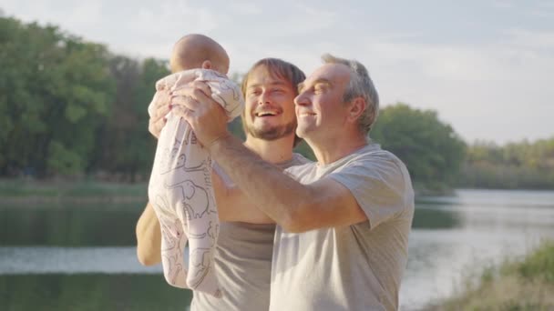Nagyapa kint tartja a kisbabát a karjában. Nagyszülő kötődés unokával. - Felvétel, videó