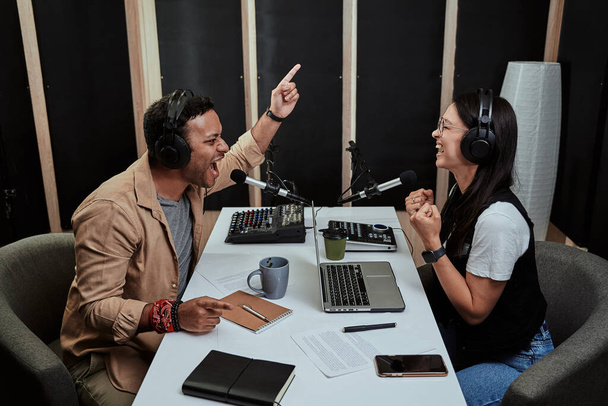 İki radyo sunucusunun portresi. Birbirleriyle konuşurken duygusal görünen genç bir adam ve kadın. Stüdyoda canlı yayın yapıyorlar. - Fotoğraf, Görsel