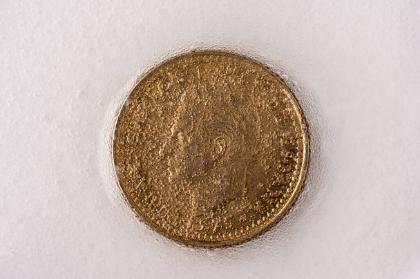 Antigua moneda de peseta con la esfinge del rey emérito español Juan Carlos I siendo limpiado entre espuma y burbujas, simbolizando la degradación de su legado - Foto, Imagen