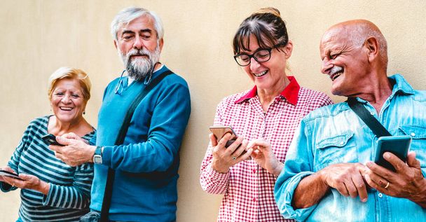 Happy senior friends having fun with modern smart phones - Συνταξιούχοι άνθρωποι μοιράζονται περιεχόμενο online με κινητά τηλέφωνα - Θετική έννοια του ηλικιωμένου τρόπου ζωής με έμφαση στη γυναίκα με γυαλιά ηλίου - Φωτογραφία, εικόνα