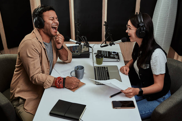 Портал о двух веселых радиоведущих, юноше и девушке, смеющихся во время обсуждения различных тем, читающих сценарий, ведущих живого шоу в студии - Фото, изображение