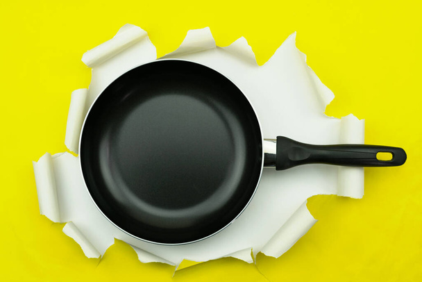 Bovenaanzicht van keukengerei pan op geel gescheurd papier achtergrond - Foto, afbeelding