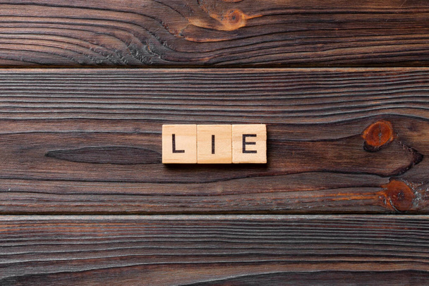 Słowo kłamstwa napisane na drewnianym bloku. Tekst kłamstwa na stole cementowym do projektowania, koncepcja. - Zdjęcie, obraz