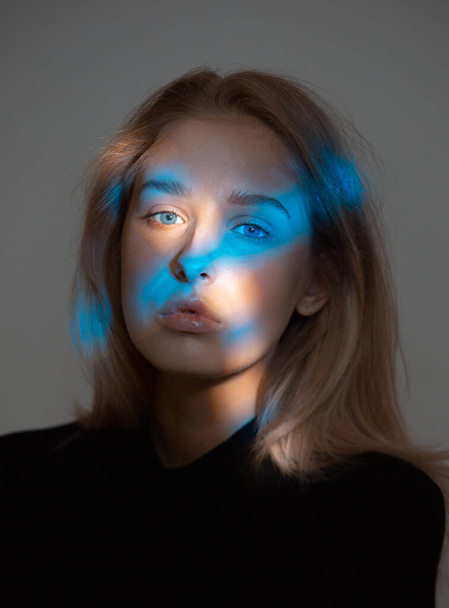 Studio portrait of young girl with spots of blue light on her face - Фото, зображення