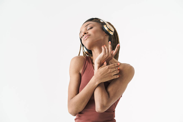 Portrait of beautiful african brunette woman with dreadlocks a listening music via wireless headphones isolated on white background - Fotoğraf, Görsel