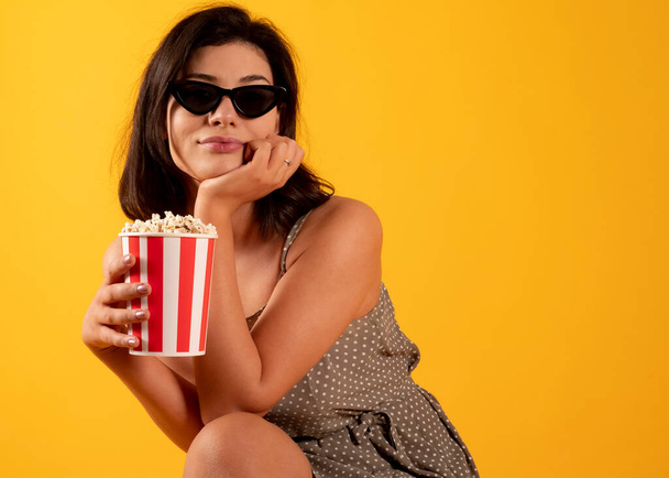femme manger du pop-corn avec des lunettes 3D sur fond jaune - Photo, image