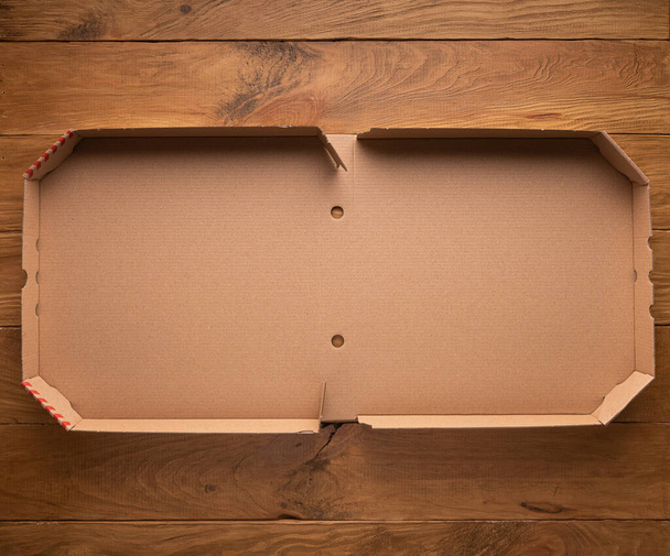 Maquette ou modèle avec nouvelle boîte à pizza vide ouverte propre en carton sur fond brun en bois naturel. Orientation horizontale. Espace de copie. Livraison à domicile et séjour concept à domicile. - Photo, image