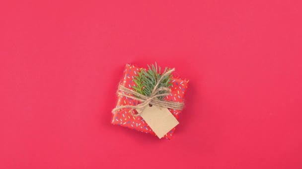 Nieuwjaar en Kerstmis presenteert 360 graden rotatie, handgemaakte geschenkdozen verpakt met rood papier en versierde dennenbomen takken, platte lay, rode achtergrond. Begrepen, ruimte. Begrippen van wenskaart. Bovenaanzicht. - Video