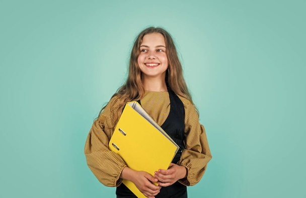 nice smile. Young business kid holding folder. Beautiful brunette girl with folder of documents in her hands. teen kid holds folder in hands. office life. get knowledge from archive - Foto, Imagen